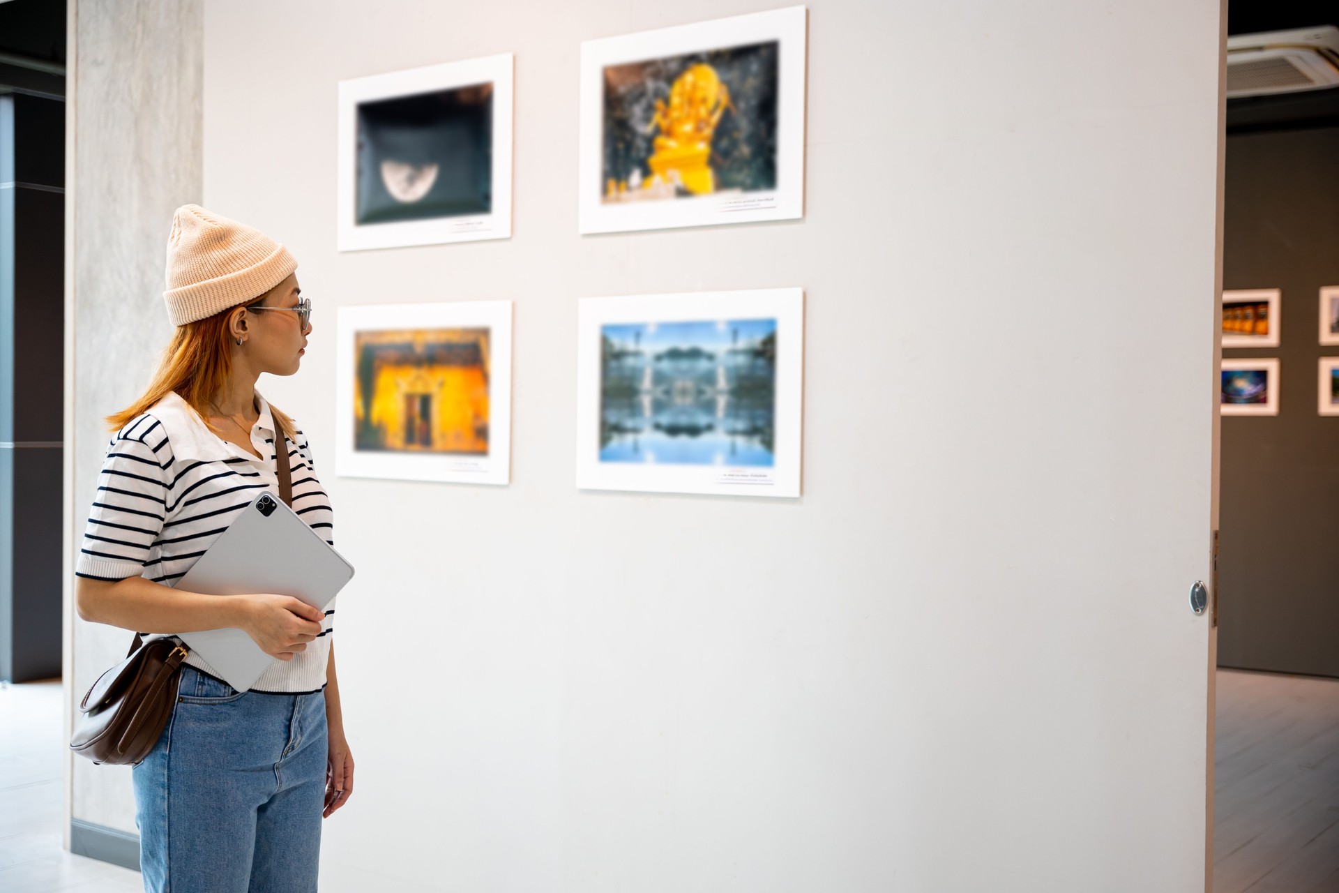 Young person at photo frame hold digital book leaning against at show exhibit artwork gallery