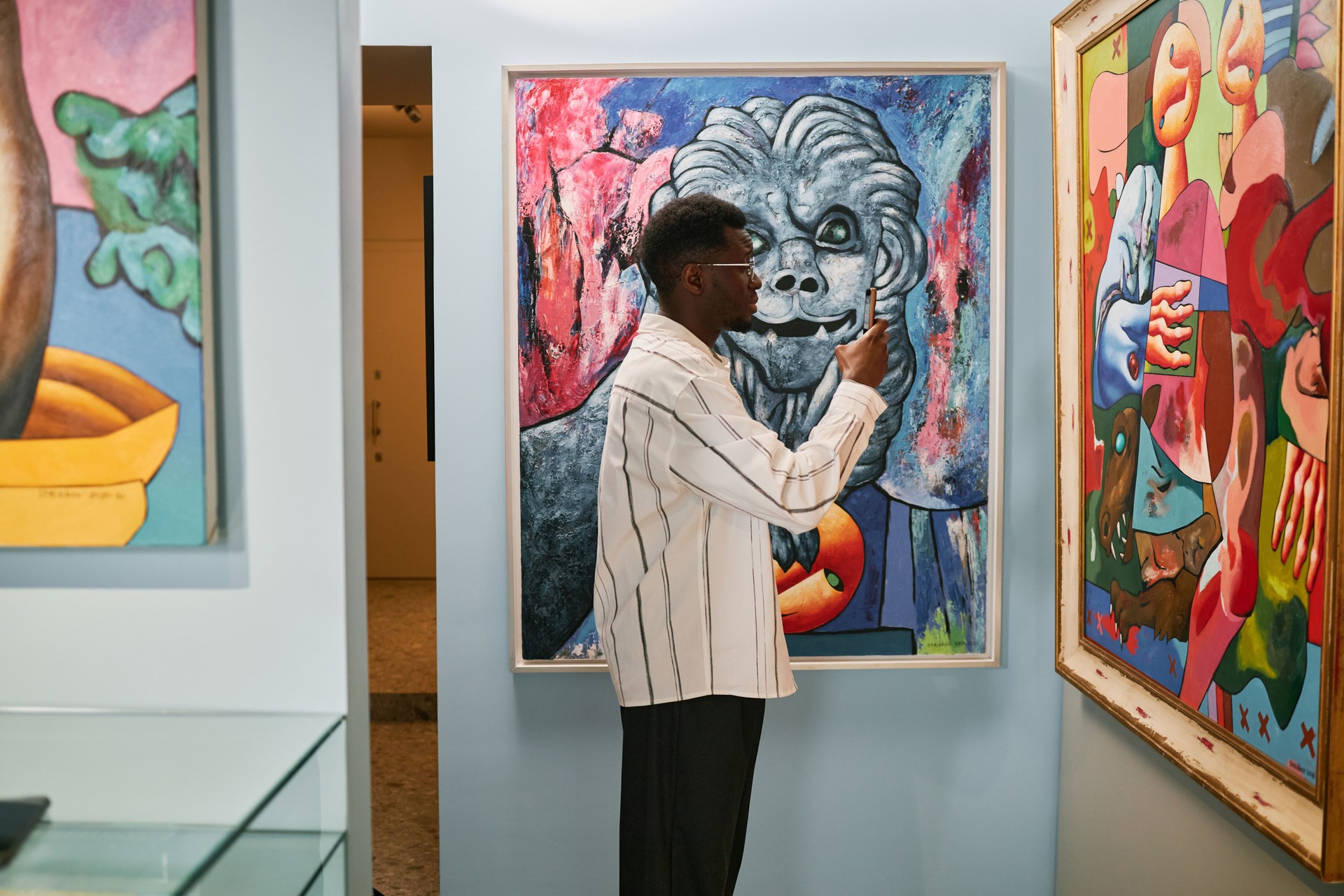 Man Observing Artworks in Museum Gallery Setting